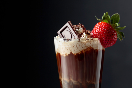 Chocolate drink with whipped cream, strawberry and pieces of black chocolate on a dark background. Copy space.の写真素材