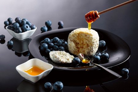 Cottage cheese with honey and blueberry on a black background.の写真素材