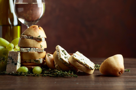 Cheese with pear, thyme and grapes on a kitchen table. Blue cheese with pear and white wine. Traditional Mediterranean snacks. Copy space.の写真素材