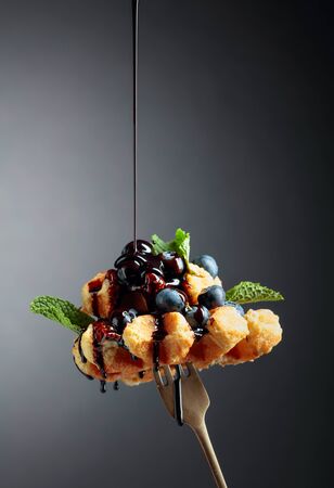 Homemade Belgian waffles with  chocolate syrup, blueberry and mint on a dark background. Copy space.の写真素材