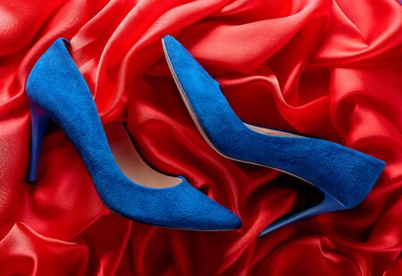 Blue women's corduroy shoes on a red silk background, top view.の写真素材