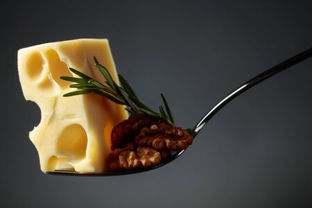 Maasdam cheese with walnuts and rosemary on a black background. Copy space.の写真素材