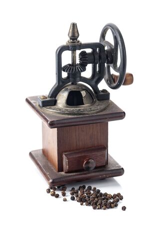 Vintage rusty, wooden black pepper grinder or mill with a mechanical handle gear isolated on a white background.の写真素材