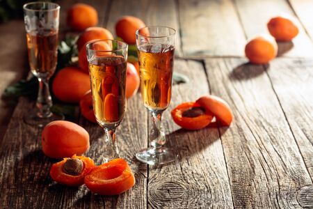 Apricot liquor and fresh apricots on a old wooden table. Wine and juicy fruits on a rustic background.の写真素材