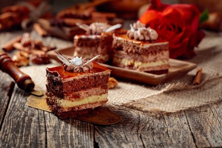 Layered cakes with spices and nuts on a old wooden table. Romantic breakfast with rose. Selective focus.の写真素材
