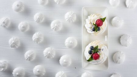 Dessert Pavlova with raspberries, blueberries and mint on a white wooden table. Top view.