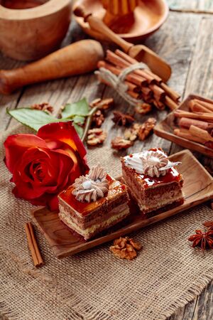 Layered cakes with spices and nuts on a old wooden table. Romantic breakfast with rose.の写真素材