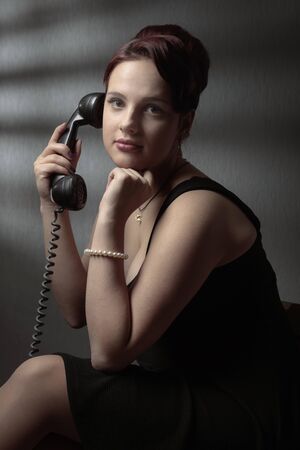 Portrait in retro style. Attractive woman in black dress with perfect hair and makeup. Girl with old...