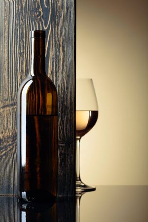 Bottle and glass of white wine on a black table. Free space for text. Focus on foreground.の写真素材