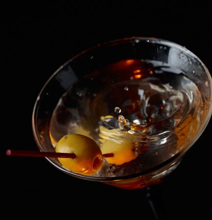 Martini cocktail with falling drops and green olives on a black background.の写真素材