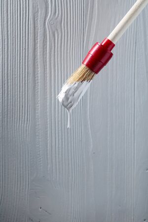 Paintbrush with white paint on a background of old wooden wall. Copy space.の写真素材