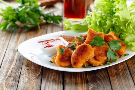 Fried chicken nuggets with ketchup sprinkled with chopped parsley.  Nuggets and salad on a old wooden table.の写真素材