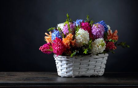Bouquet of hyacinths in a white basket, dark background. Copy space.