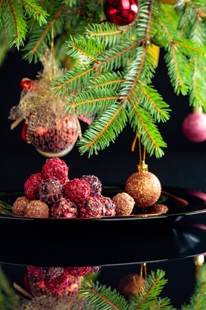 Various chocolate truffles on a black plate and Christmas tree.の写真素材