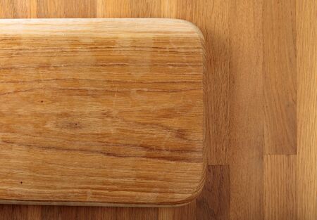 Wooden cutting board on a oak table. Top view.の写真素材