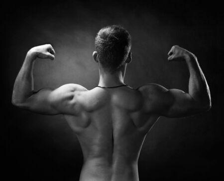 Brutal strong bodybuilder athletic fitness man pumping up muscles workout bodybuilding. Black and white.の写真素材