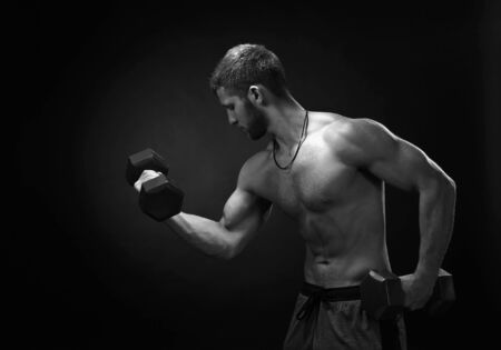 Brutal strong bodybuilder athletic fitness man pumping up muscles workout bodybuilding. Black and white.の写真素材