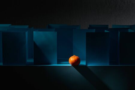  Tangerine in paper labyrinth. Concept of theme of bureaucracy. Copy space.