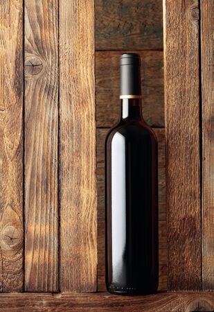 Bottle of red wine on a old wooden background. Free space for your content.の写真素材