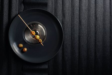 Dry martini with green olives on a black background. Top view, copy space.の写真素材