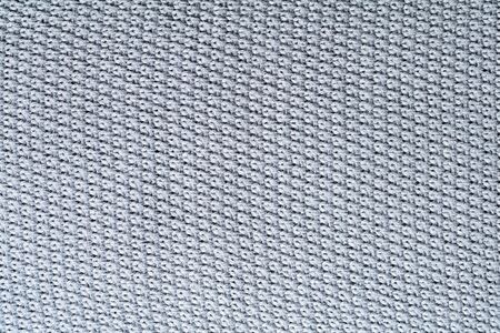 Grey knitting fabric texture background. Knotted carpet closeup.