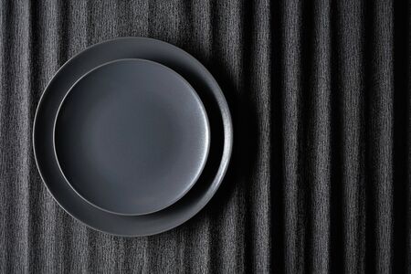 Empty black plate on a black background. Top view, copy space.