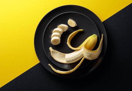 Ripe juicy banana on a black plate. Top view, copy space.の写真素材