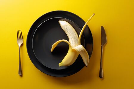 Ripe juicy banana on a black plate. Top view, copy space.の写真素材