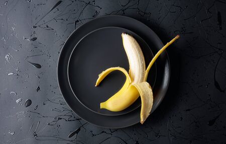 Ripe juicy banana on a black plate. Top view, copy space.の写真素材