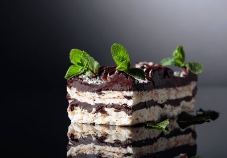Delicious chocolate cake with mint on a black reflective background.  Copy space.の写真素材
