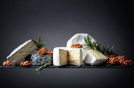 Various soft cheeses with walnuts and rosemary. Copy space.