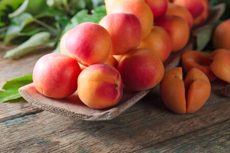 Juicy apricots with leaves on a old wooden table.の写真素材