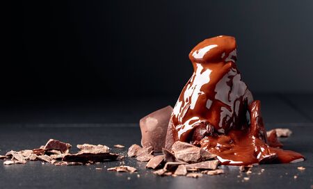 Broken large piece of dark chocolate with crumbs on a black table.の写真素材
