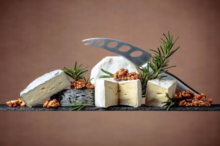 Various soft cheeses with walnuts and rosemary. Copy space.
