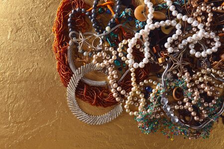 Various jewelry on a gold background, top view.の写真素材