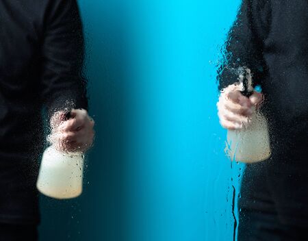 Two mans in rubber gloves sprays disinfectant on a glass, selective focus. Copy space.の写真素材