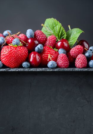 Berries closeup colorful assorted mix on a dark stone background. Copy space.の写真素材