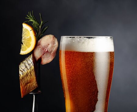 Beer and smoked mackerel with lemon slice on a dark background. の写真素材