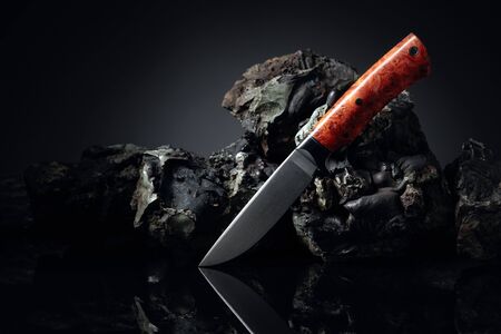 Hunter combat hand made knife and broken stones. The blade has a beautiful damask pattern, handle - titan and elm.の写真素材