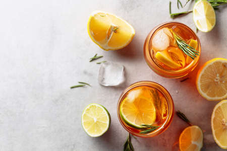 Traditional iced tea with lemon, lime and ice garnished with rosemary twigs. Top view. Copy space.