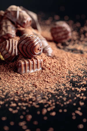 Chocolate candies on a black background sprinkled with chocolate chips.の写真素材