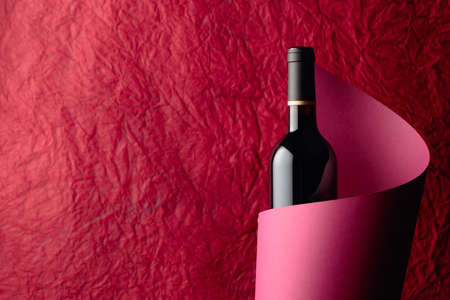 Bottle of red wine on a red background. Free space for your content.の写真素材