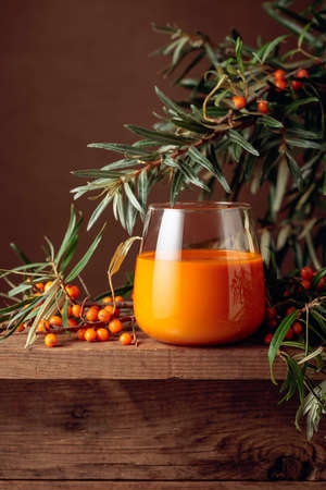 A glass of sea buckthorn juice with fresh berries on an old wooden table. Healthy and diet food. Copy space.の写真素材