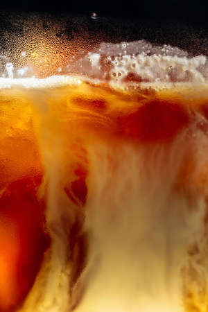 Cream being poured Into iced coffee. Macro shot, copy space.の写真素材