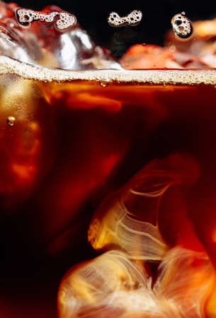 Cream being poured Into iced coffee. Macro shot, copy space.