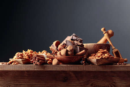 Various chocolates with ingredients. On a old wooden table candy, coffee beans, cinnamon, anise,...