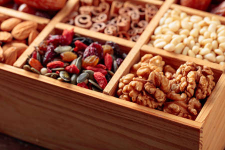 Dried fruits, various nuts and seeds in old wooden box. Selective focus.