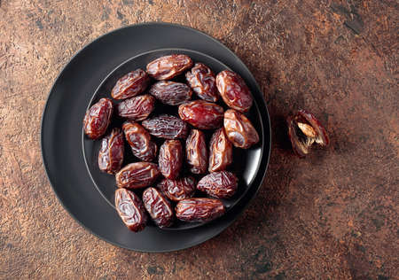 Dried sweet dates on a black plate, top view.の写真素材