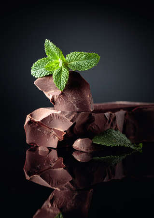 Large piece of dark bitter chocolate with mint on a black reflective background. Copy space.の写真素材
