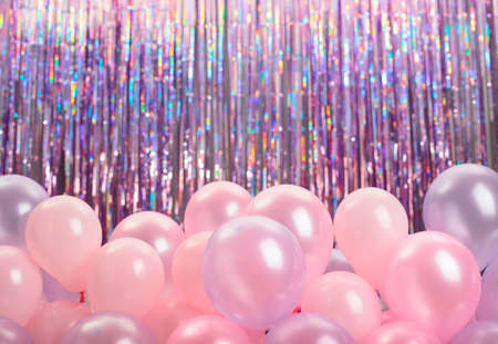 Pink and purple balloons on colorful background with bokeh defocused lights.